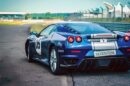 Plavi Ferrari sa reklamama i belom štraftom po sredini na trkačkoj stazi
