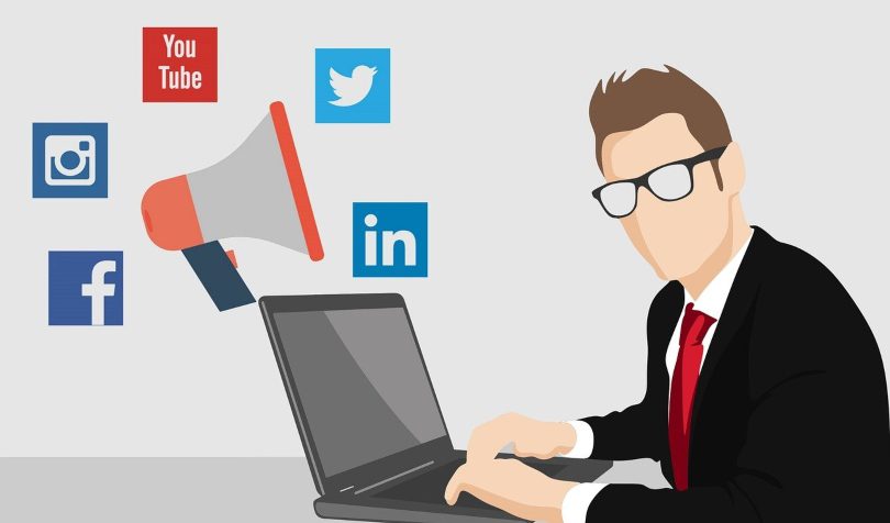 Ilustracija poslovnog čoveka koji radi na laptopu, u pozadini ikonice društvenih mreža