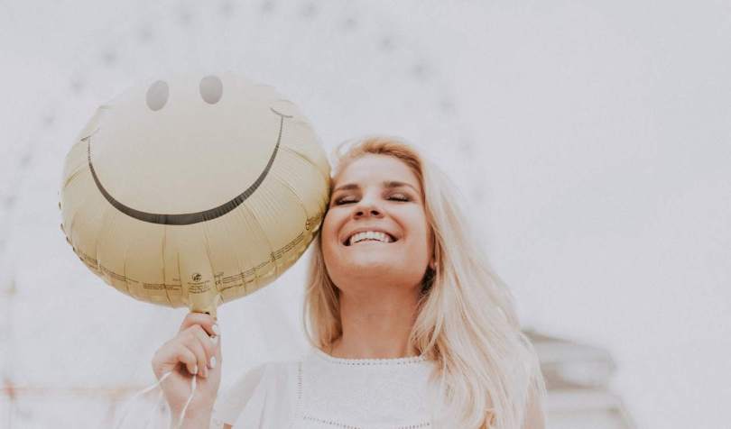 Namejana žena drži balon sa smajlijem