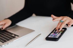Žena koristi telefon i laptop u kancelariji