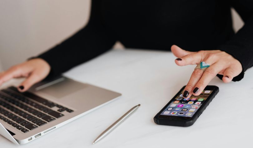 Žena koristi telefon i laptop u kancelariji