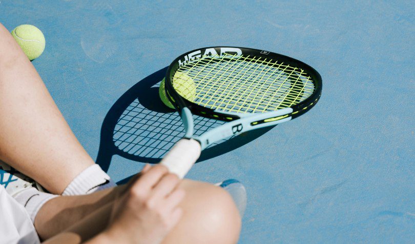 Osoba drži reket za tenis na terenu