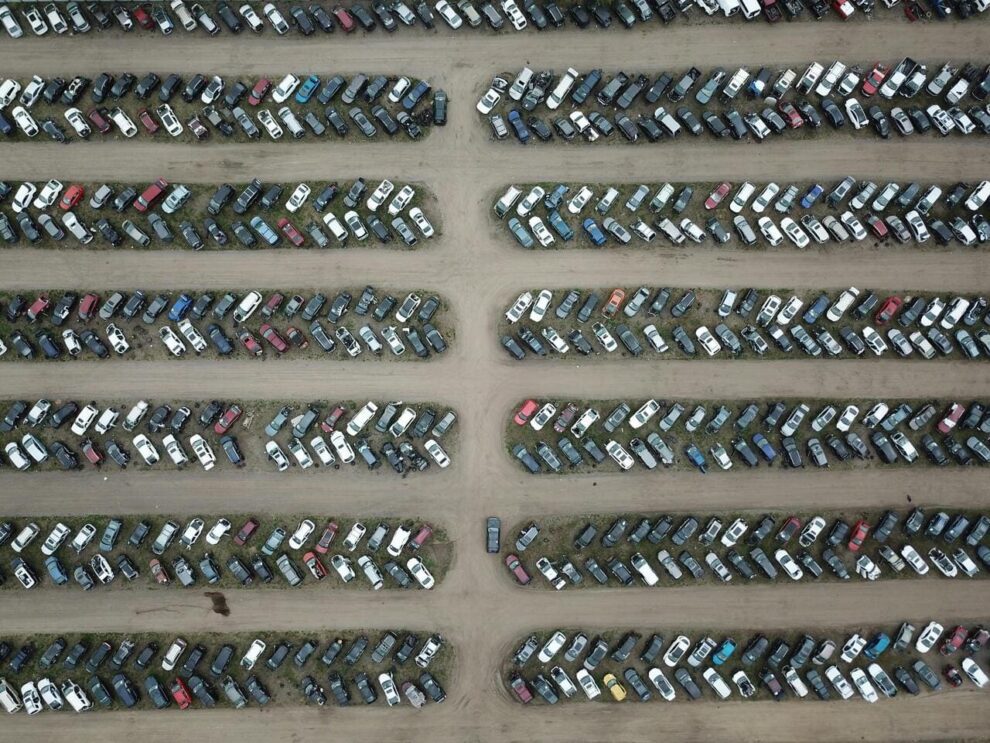 Pogled iz vazduha na dugačke redove parkiranih automobila na zemljanom terenu