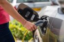 Žena puni sivi električni automobil na otvorenom